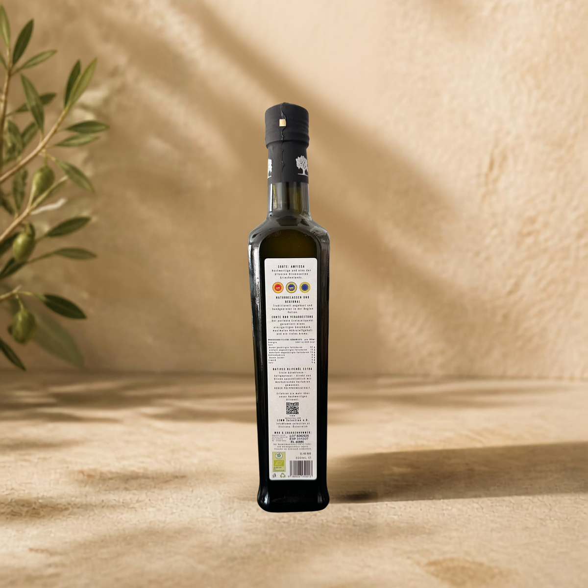 Bio Olivenöl Extra Nativ von LEMM Selection im mediterranen Ambiente mit Olivenzweig, Rückseite der Flasche